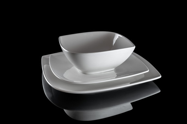 白瓷瓷盘俯视图。在黑暗的背景下，晚餐用的空方形盘子。清洗圆瓷陶器。早餐餐具。图片下载