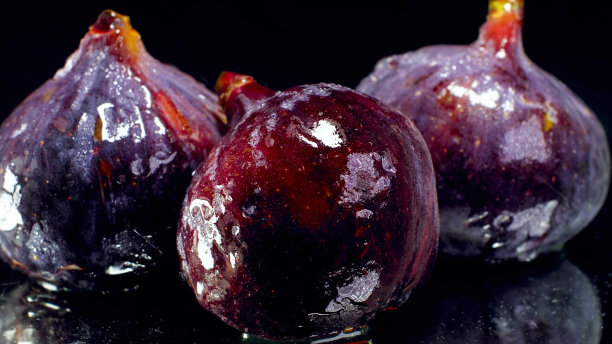 近景照片潮湿的成熟无花果在黑色的背景。季节水果的摘要背景图片下载