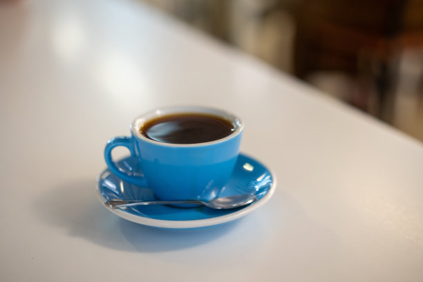 桌上放着蓝色咖啡杯里的黑咖啡图片下载