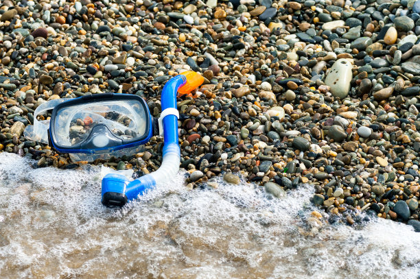 在卵石滩上潜水用的蓝色通气管和面罩。图片下载