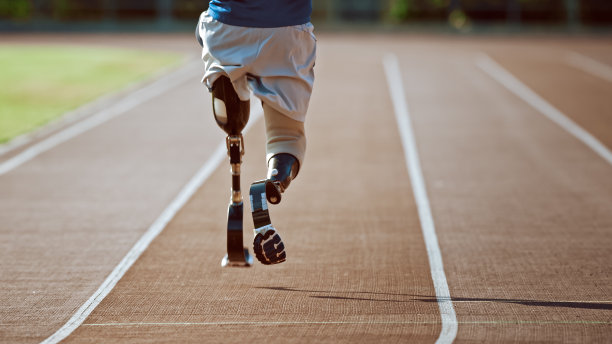 运动残疾人健美儿戴着义肢跑步刀片在阳光明媚的下午在户外体育场训练。截肢跑步者在体育场跑道上慢跑。激励运动镜头。的腿。图片下载