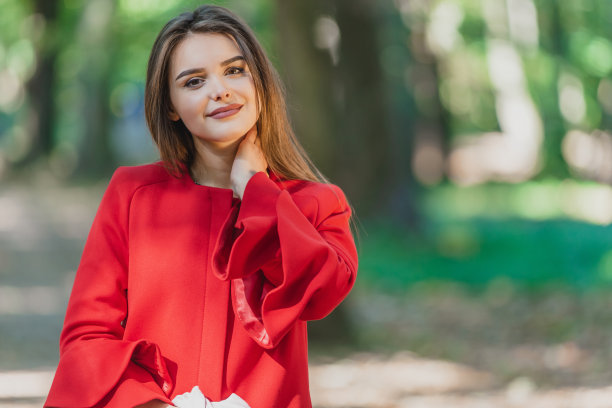 图片中可爱的黑发女孩抚摸着她的脖子，在模糊的公园背景下看起来天真而真诚。图片下载