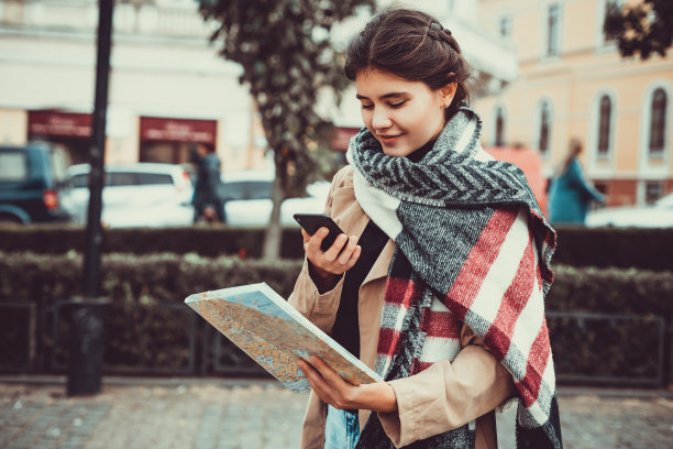 白人女性游客在街上搜索城市地图和智能手机gps。图片下载