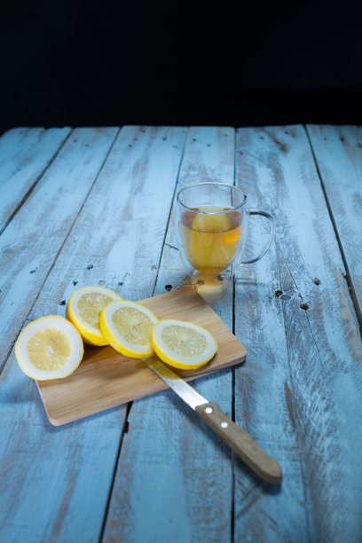 一杯美味的柠檬茶，放在切柠檬片的砧板旁边图片下载