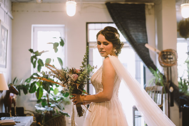 优雅的早晨的照片。的婚礼。新娘。准备。新娘拿着一束花靠近窗户。欧式婚礼。早晨新娘在婚礼当天等待新郎图片下载