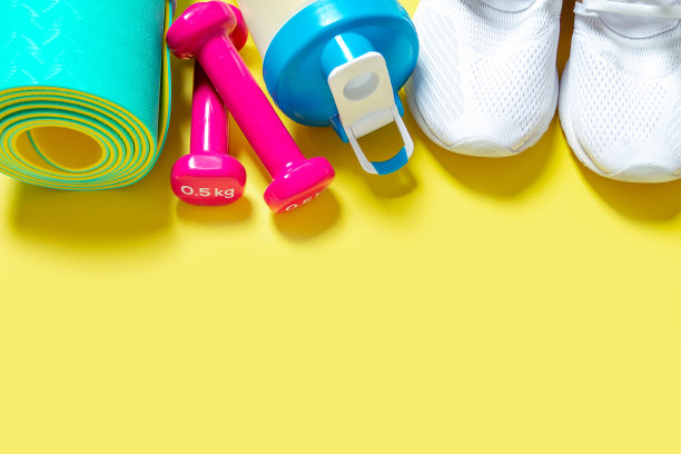 平躺运动和健身设备，粉色哑铃，运动鞋，水搅拌机瓶和薄荷瑜伽垫在黄色的背景。顶部视图与复制空间。健康的生活方式。图片下载