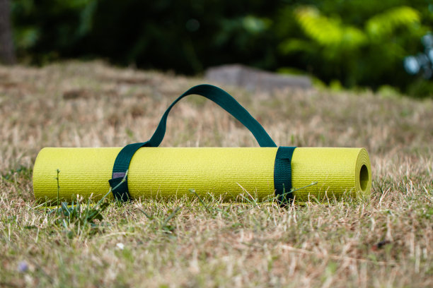 裁剪图像的女孩滚动瑜伽垫。特写的迷人的年轻女子折叠绿色瑜伽或健身垫后，在树林或城市公园的林间空地。健康的生活图片下载