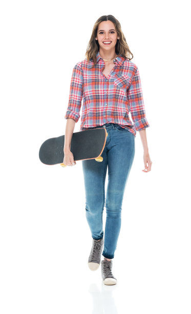 白人年轻女子穿着裤子在白色背景前玩滑板图片下载