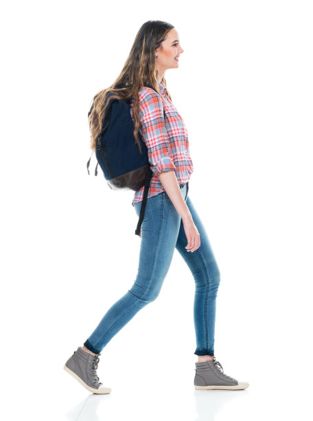 年轻的白人女大学生背着背包拿着包走在白色背景的前面图片下载