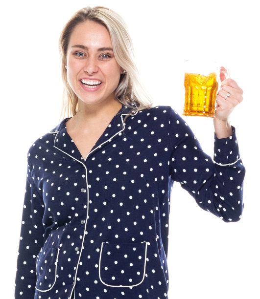 白人女性站在白色背景前穿着睡衣，拿着酒图片下载