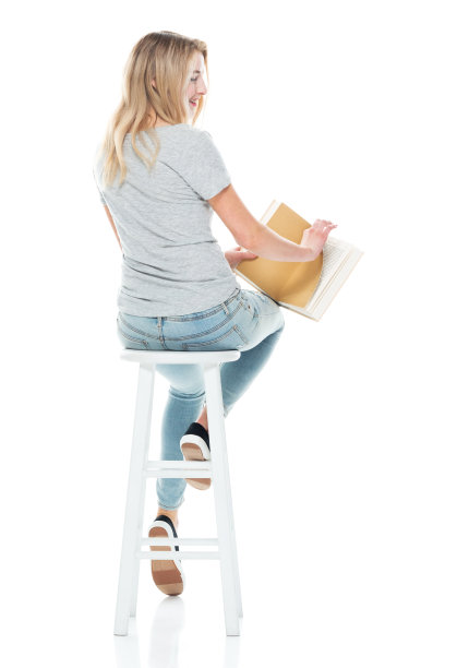 z一代的少女学生坐在白色背景前，穿着牛仔裤，拿着书图片下载