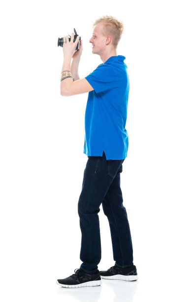 白人男性游客站在白色背景，穿着马球衫，拿着相机图片下载