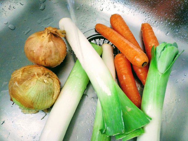 在厨房水槽中清洗韭菜、胡萝卜和洋葱图片下载