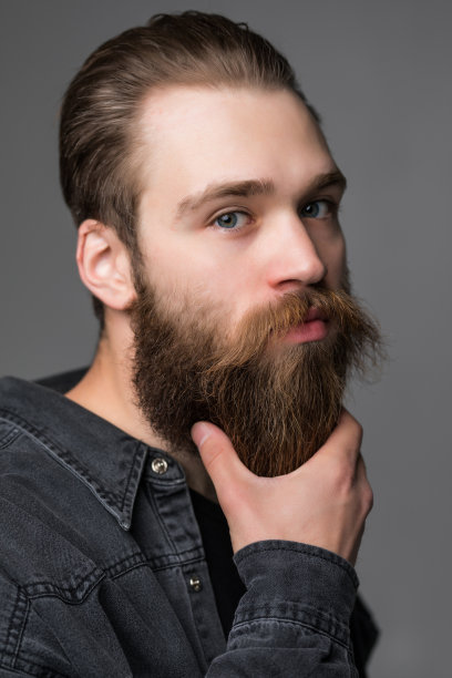 特写的男人触摸他的长胡子和胡子孤立在灰色的背景图片下载