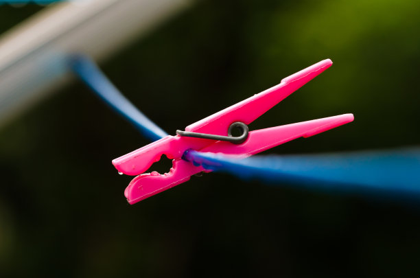 一根蓝色的衣服线，上面有许多雨滴，放在深色的背景上，雨后有一个粉红色和蓝色的夹头。复古洗衣服的方式。图片下载