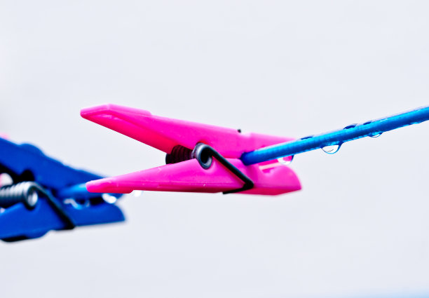 一条蓝色的衣服线，上面有许多雨滴，放在深色的背景上，雨后用一个粉红色的钉子钉住。复古洗衣服的方式。图片下载