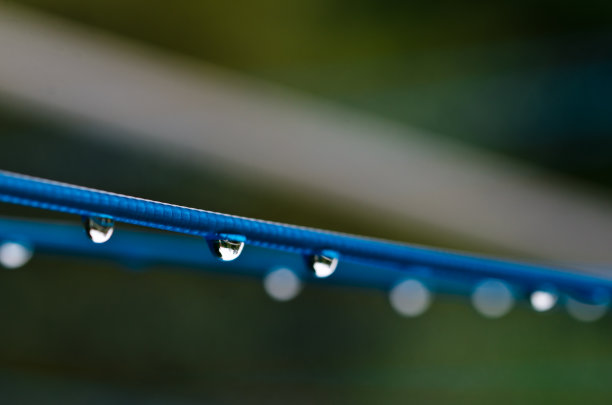 雨后，在黑暗的背景前，一条有许多雨滴的蓝色衣服线。复古洗衣服的方式。图片下载
