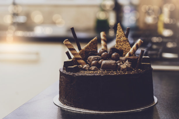 家庭制作的巧克力布朗尼与模糊的厨房背景，巧克力软糖蛋糕与金黄装饰，生日蛋糕的想法图片下载