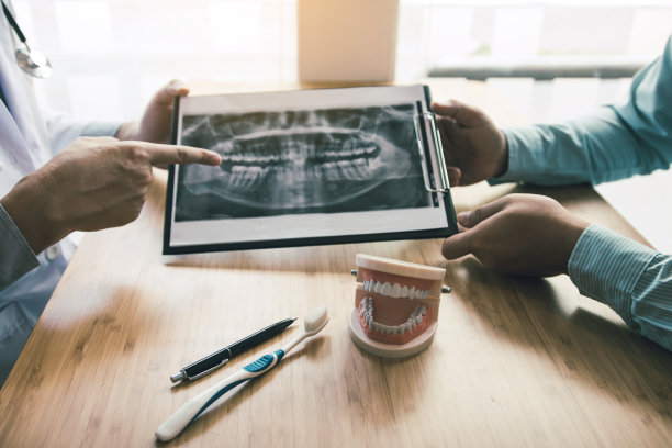 牙科医生在给病人报告x光片时正在讨论牙科问题。图片下载