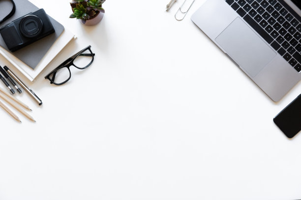 俯视图白色办公桌与笔记本电脑，智能手机和用品。顶部视图与复制空间。图片下载