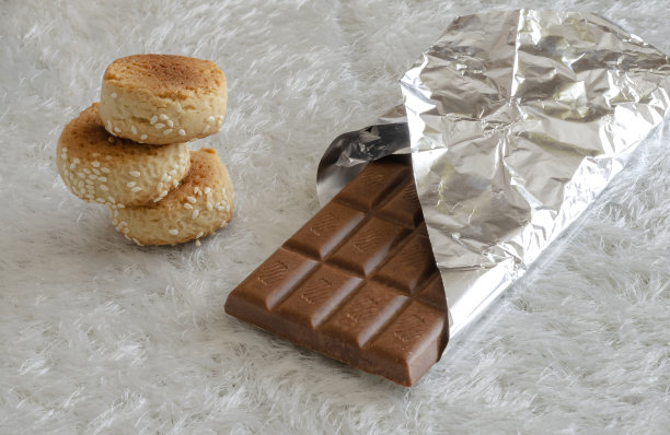 多孔的牛奶巧克力和自制的芝麻饼干在闪亮的白色背景。图片下载