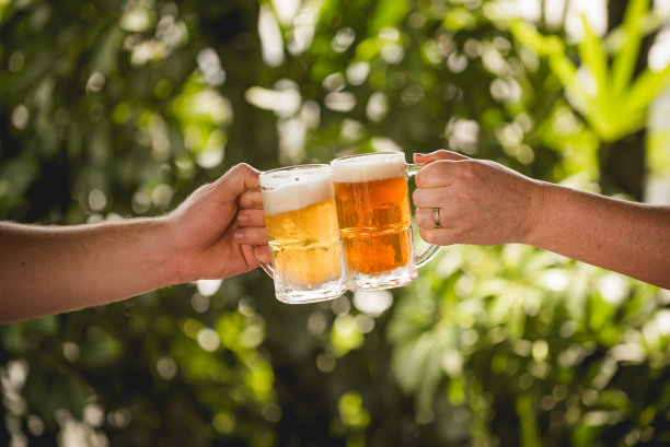 两个人拿着装满排骨的杯子互相敬酒。图片下载