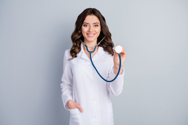美丽开朗的专业家庭医生女士用听诊器检查病人的照片，听心跳，检查呼吸系统，穿着白色实验服，孤立的灰色背景图片下载