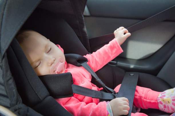 小女孩睡在汽车安全座椅里。儿童系上安全带，安全驾驶。特写镜头。侧视图。图片下载