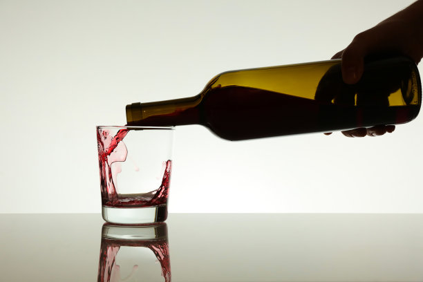 红酒正从瓶子里倒进玻璃杯里图片下载
