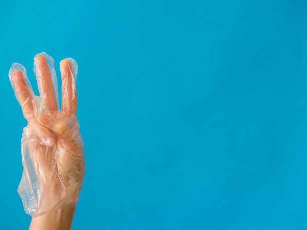 手戴塑料手套，三根手指放在蓝色背景上图片下载