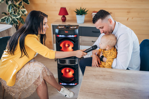 父母和他们的宝贝儿子在家里唱卡拉ok图片下载