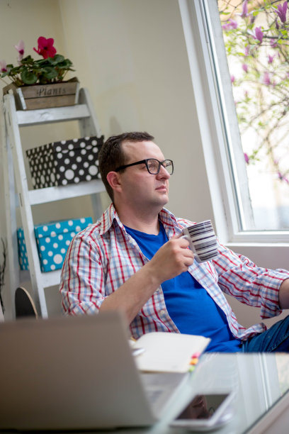 这张照片拍摄的是一个年轻的商人在他的办公桌前喝咖啡休息图片下载