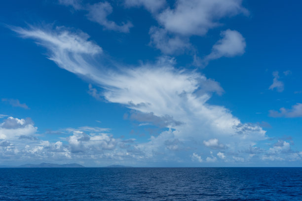 蓝色天空中缕缕白云在海上的照片图片下载