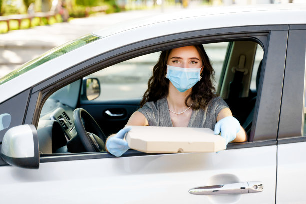 带着医用口罩和手套的披萨盒在车里的学生。送餐服务开车。根据社交距离提供安全食品。美味的披萨，香肠，奶酪，西红柿装在纸盒里图片下载