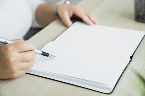 女人在家里桌子上的空白笔记本上手写。图片下载
