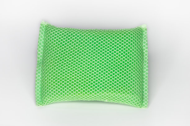 新的洗碗海绵是绿色的，有一个网状覆盖海绵和白色的背景。图片下载