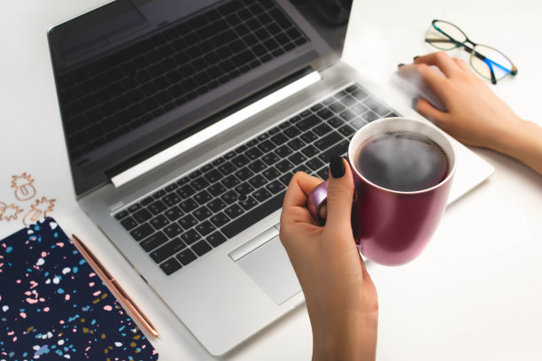 女人的手在笔记本电脑上工作俯视图。家庭办公，在线教育。电脑粉红杯锁定图片下载