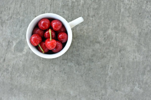 白色杯子里的熟透的甜樱桃，灰色背景图片下载