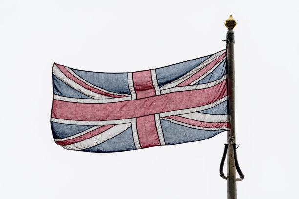 英国国旗(英国国旗也被称为联合国旗)在一个雨天吹向多云灰色的天空图片下载