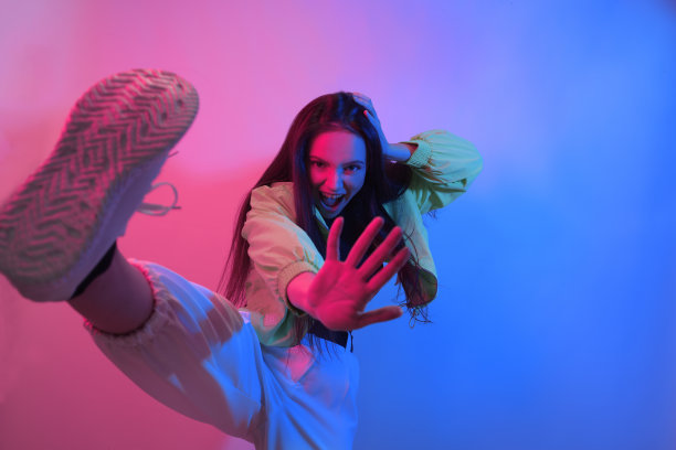 褐发女郎穿着霓虹灯跳舞，舞者穿着红蓝色。嘻哈女孩，派对，微笑。模型在飞行，跳跃。明亮的照片,情感。图片下载