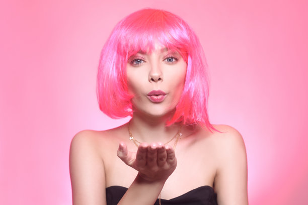 一个女孩戴着粉色的假发，穿着粉色的服装，画着粉色的妆，表情严肃，模特正在拉屎。一个有着蓝色眼睛的女孩明亮的照片肖像图片下载