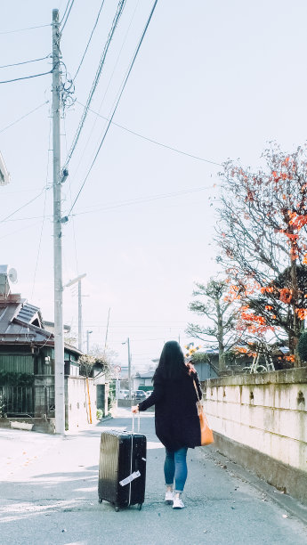 一个罕见的亚洲妇女走在街上带着一个旅行箱在日本。图片下载