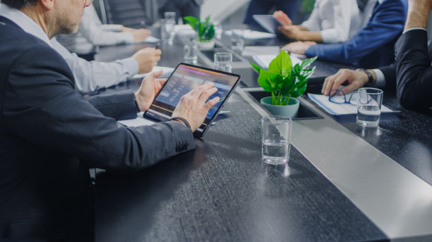 在企业会议室，商务人员手中的特写，与使用数字平板电脑签订合同。坐在会议桌前的人图片下载