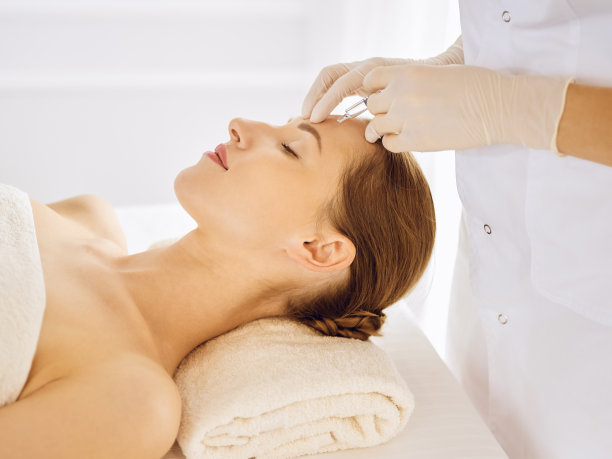 闭着眼睛接受美容注射的美女。美容师医生用注射器给女性脸部做美容手术图片下载