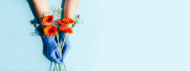 女性的手在医疗手套与美丽的鲜花。图片下载