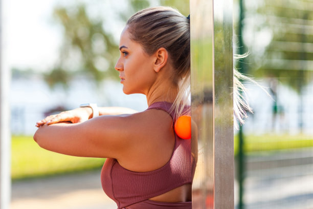 年轻的女运动员在紧顶倚在小球上修复背部疼痛，按摩僵硬的肌肉和酸痛的颈部图片下载