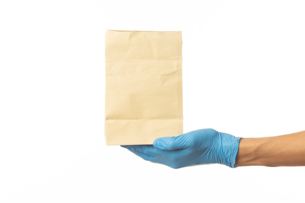 近距离送货员手在医疗手套拿食品纸袋隔离在白色背景，包装模型，送货服务理念图片下载