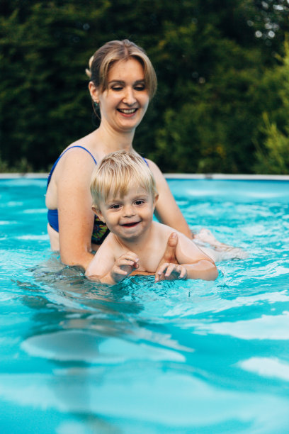 母亲和儿子在室外游泳池嬉水嬉戏图片下载