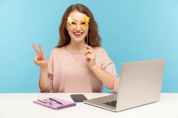 有趣乐观的女员工用明亮的纸眼镜遮住眼睛，表现出胜利的姿态，玩得很开心图片下载