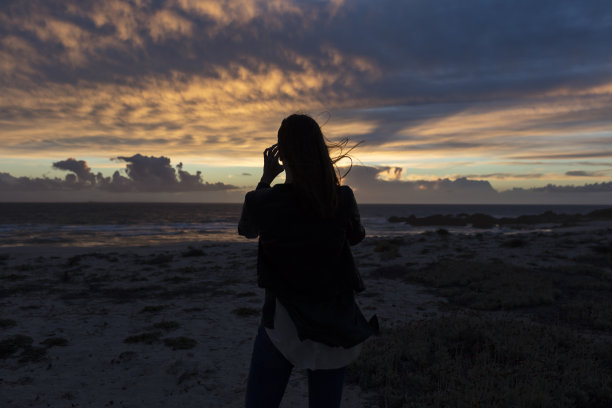 年轻女子拍摄壮丽的日落景色图片下载